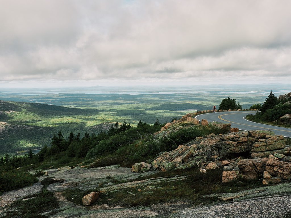 A solitary cyclist follows the curving ascent up Cadillac Mountain, the tallest peak in Acadia National Park.